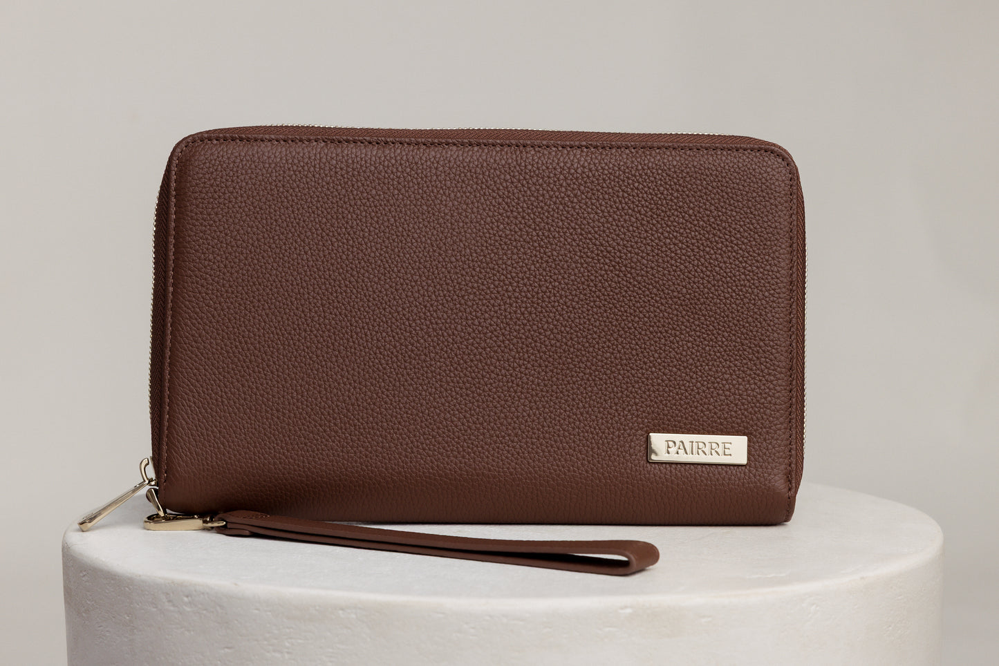 Pairre 4P passport wallet in brown full-grain leather — closed exterior showing PVD gold hardware Pairre 4P passport wallet in brown full-grain leather — closed exterior showing PVD gold hardware