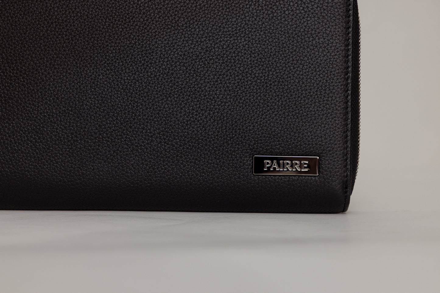 Pairre 4P black leather passport wallet — close up of PVD gold Pairre hardware plate