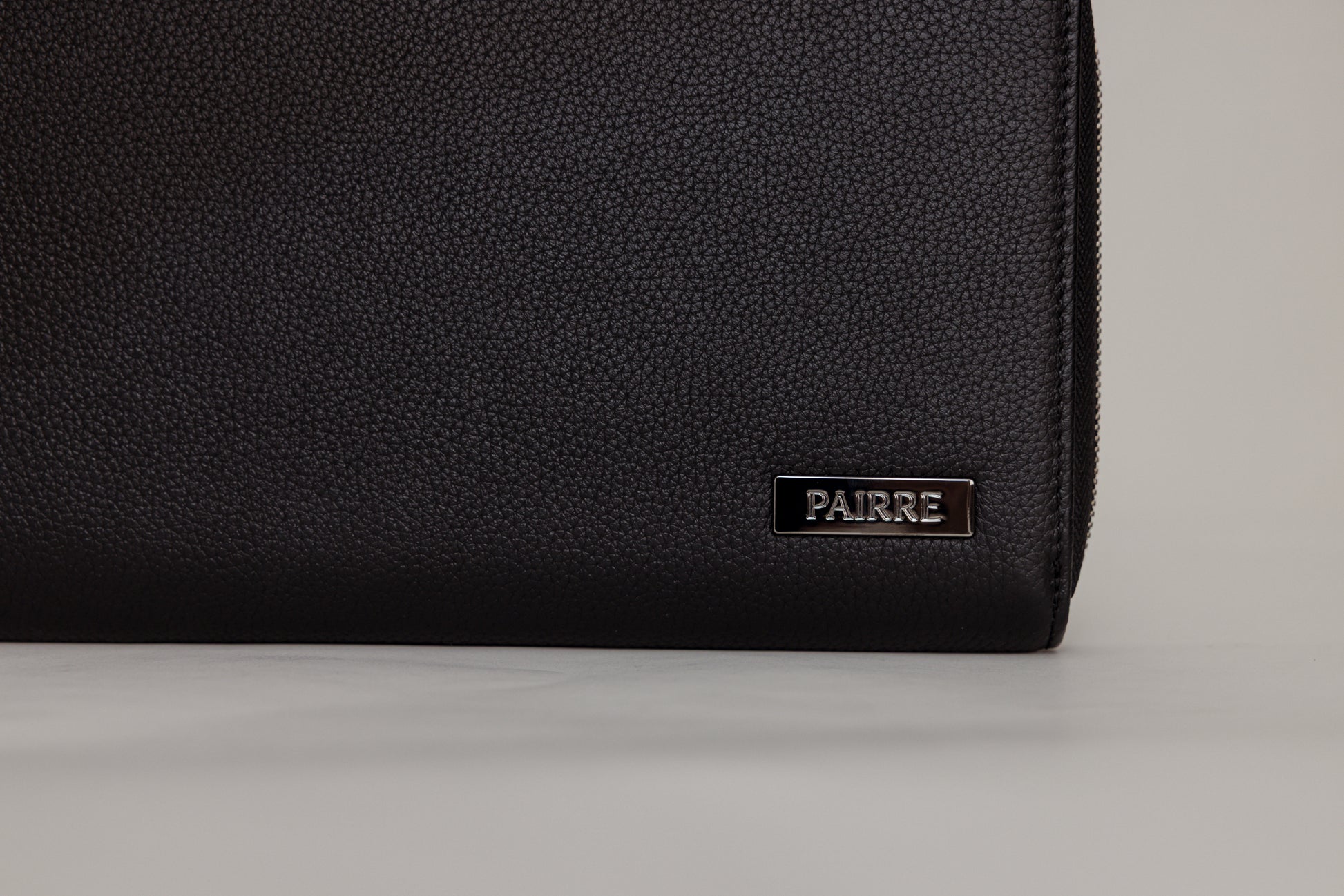 Pairre 4P black leather passport wallet — close up of PVD gold Pairre hardware plate