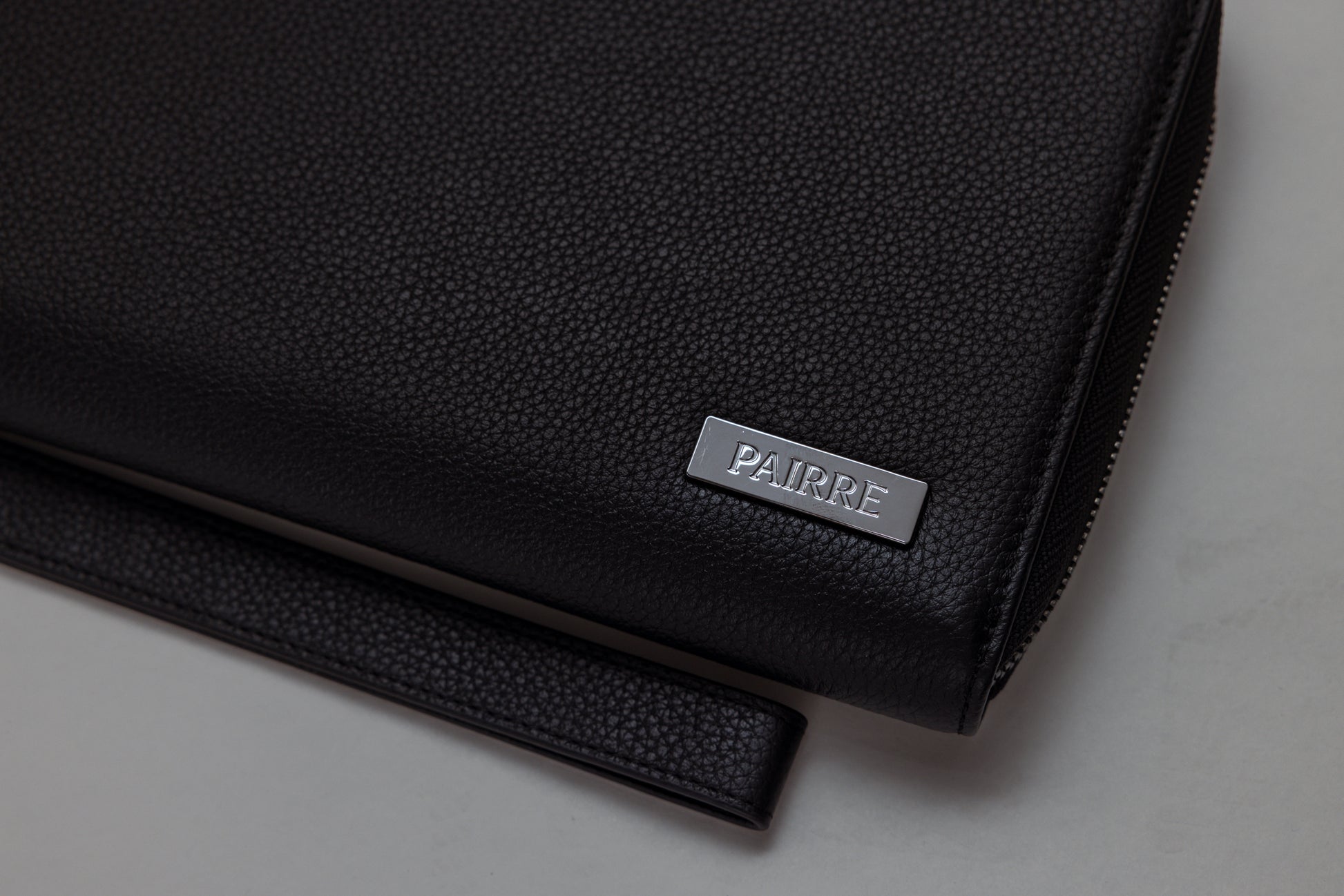 Pairre 4P black leather passport wallet — close up of PVD gold Pairre hardware plate