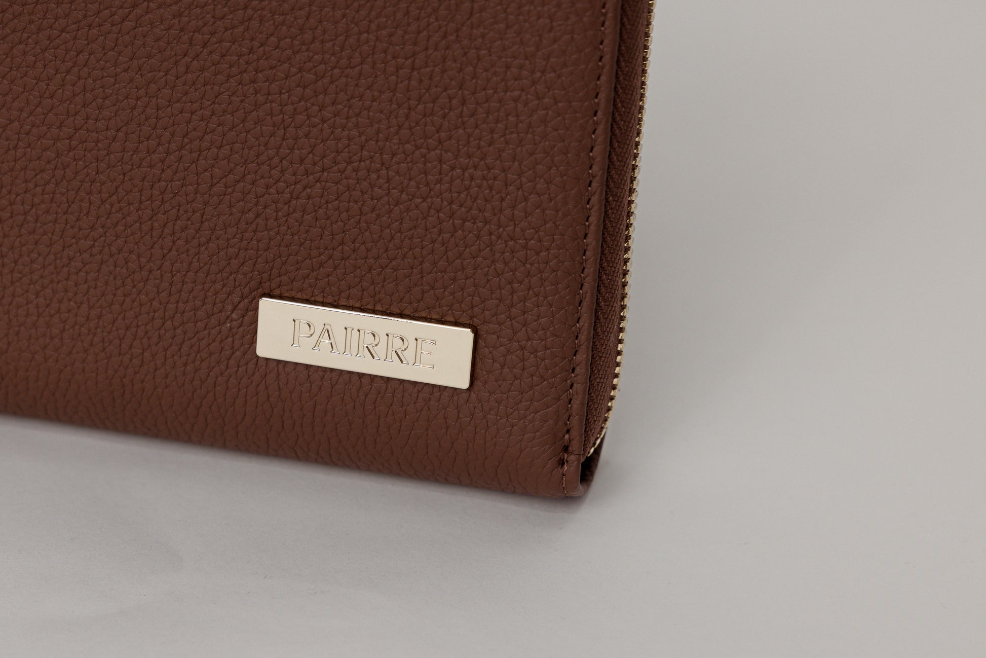 Pairre 2P brown/espresso leather passport wallet — close up of PVD gold Pairre hardware plate