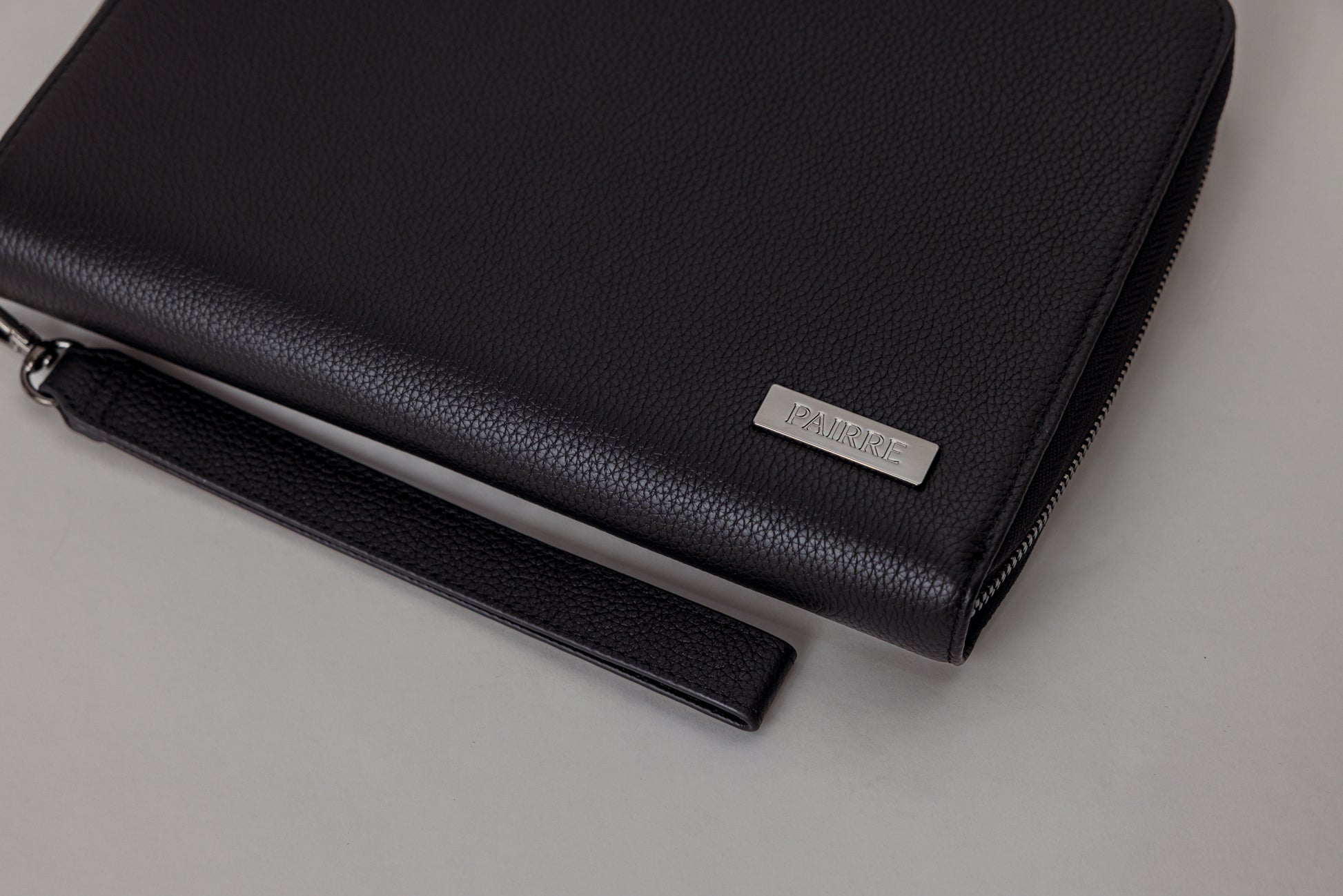 Pairre 8P black leather passport wallet — close up of PVD gold Pairre hardware plate
