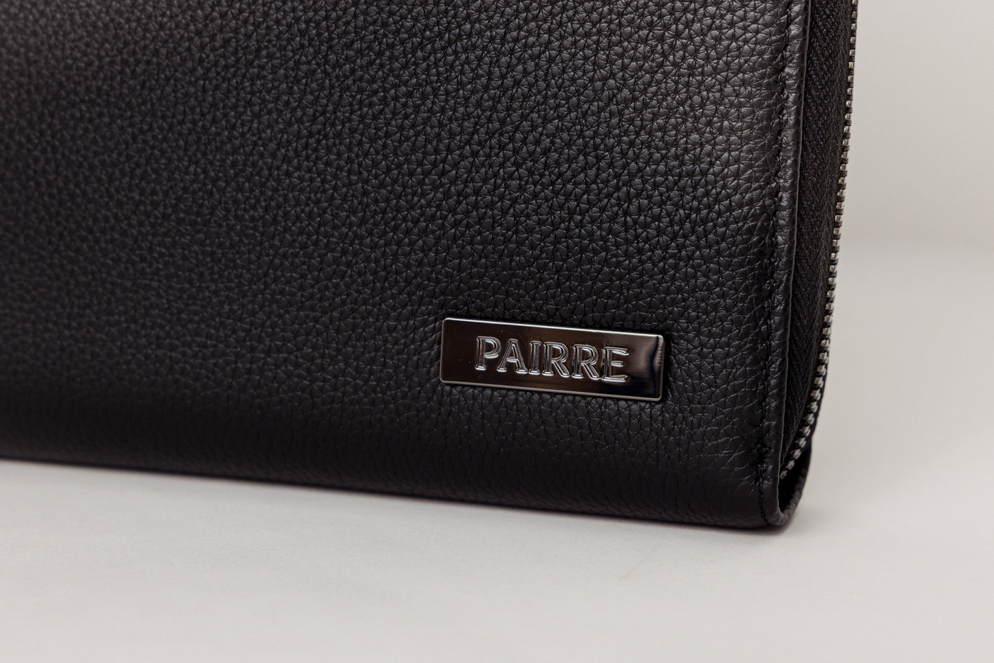 Pairre 8P black leather passport wallet — close up of PVD gold Pairre hardware plate