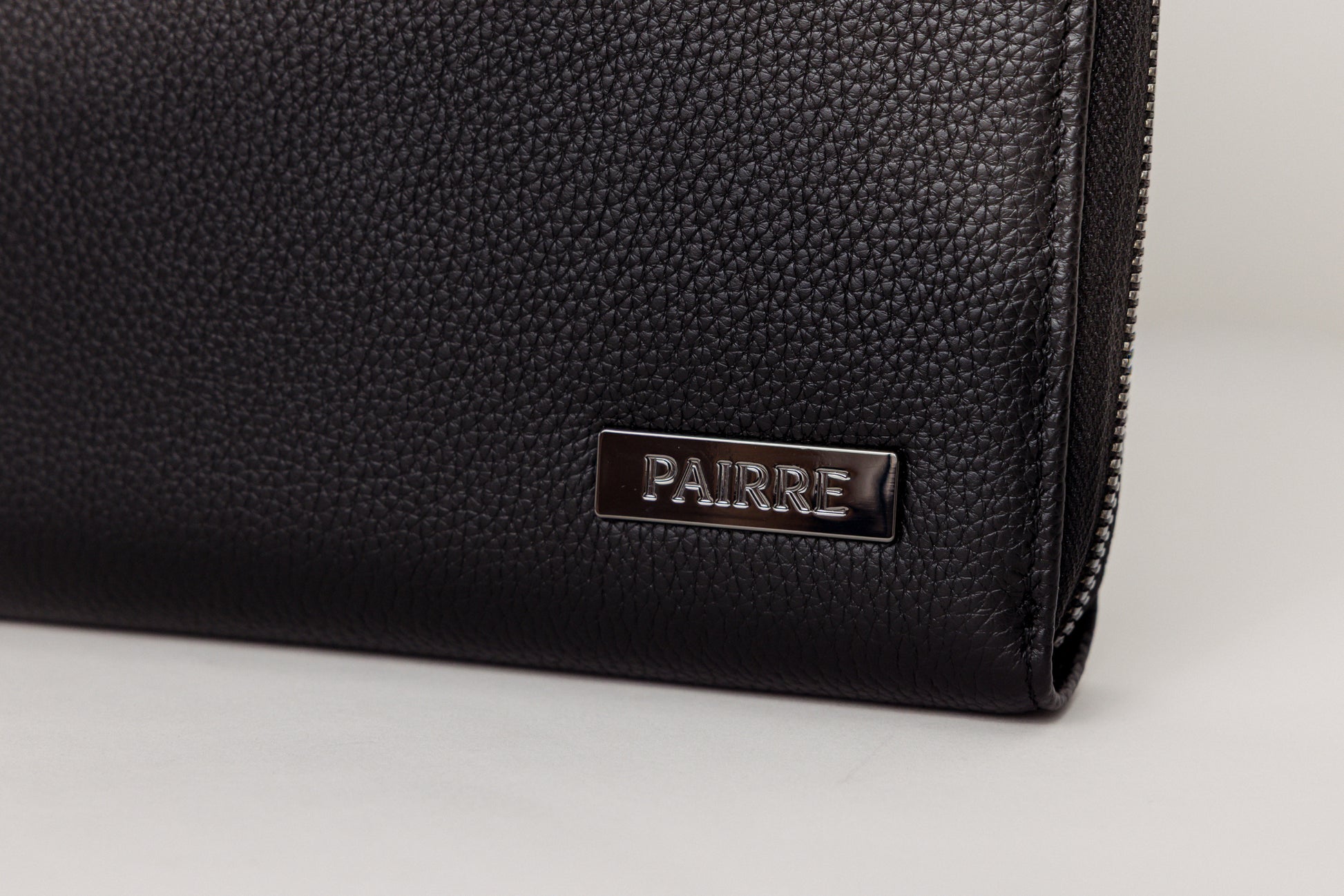 Pairre 8P black leather passport wallet — close up of PVD gold Pairre hardware plate